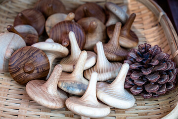 Pile of wooden whirligig toys and a pine cone in a wicker basket as decorative items.
