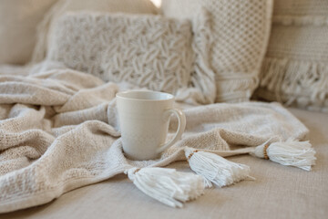 Fototapeta na wymiar Autumn or winter composition. Cup of coffe on knitted blanket on white sofa. Flat lay, top view