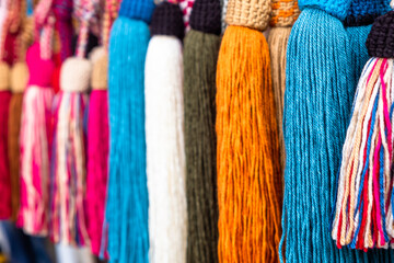 Rows of colorful handmade tassels hanging as decorative items.
