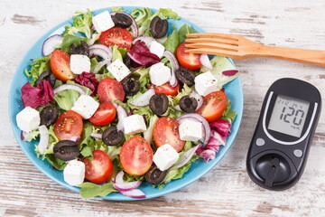 Glucometer for checking sugar level and fresh greek salad. Diabetes and healthy lifestyles