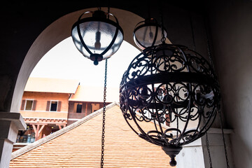 Decoration of a black wrought iron lamp with beautiful vintage pattern and two glass lamps with black frame hanging from the ceiling.
