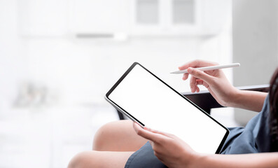 Cropped photo hand of young female using  tablet with stylus pen while sitting in living room at...