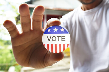 Man holding vote button for the November elections in the United States 2020, blurred background.