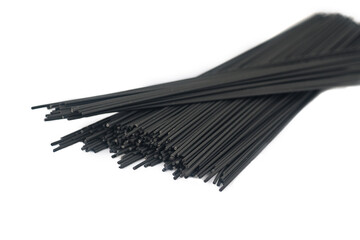 Raw black homemade spaghetti bunch isolated on white. Dry black noodles macaroni bundle.