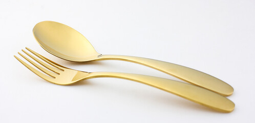 Elegant and expensive golden spoon and fork are placed on a white background.