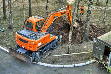 Mini excavator digging a trench among the trees for repairing city communications © timltv