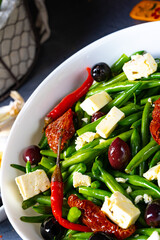 Spicy green bean salad with olives, feta cheese and dried tomatoes