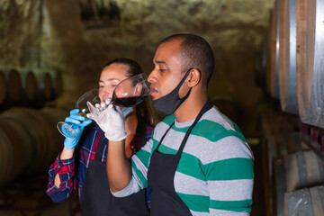 Obraz na płótnie Canvas Specialists in a protective mask checking ageing process of wine