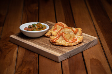 Traditional Spanish tapas with tomatoes, greens and tomato sauces on the wood plate board. Fried meat pies. Fish, seafood. High quality photo.