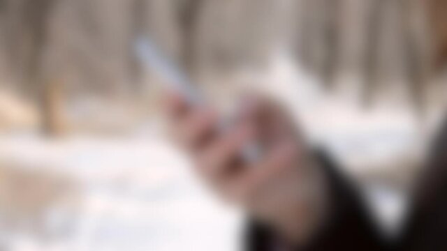 Blurred background. Girl holding smart phone and work on it, typing a message