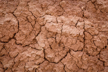 Close up image of brown dry soil texture. Abstract pattern of red-hot cracked clay. Lifeless desert background.