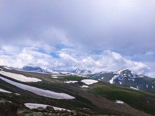landscape in the mountains having melting snow and cloud sky