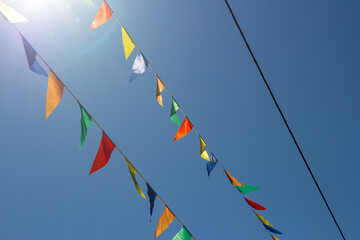 Colored flags stretched in the air against a blue sky. Festive street decoration
