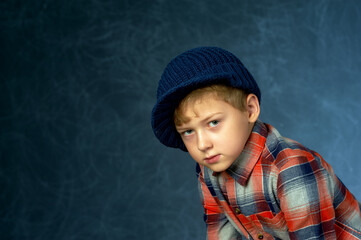Portrait of a boy in a knitted hat in the Studio on a dark background .