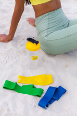 Close no head shot of sporty fit slim woman wearing sport wear, rubber bands and protein shaker lie next to. 