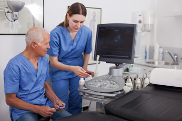 Portrait of elderly man doctor and woman nurse in cabinet of ultrasound test