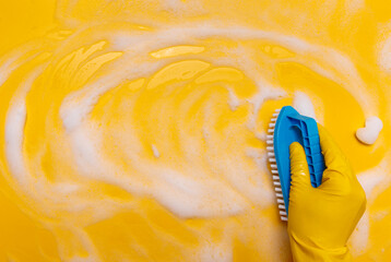  wipe the foam on a yellow background with a blue gloved brush.