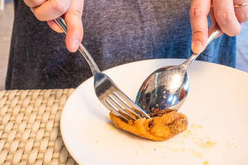 Spoon and fork are dipping the fried chicken on a white plate. Eating fried chicken so as not to stain your hands.