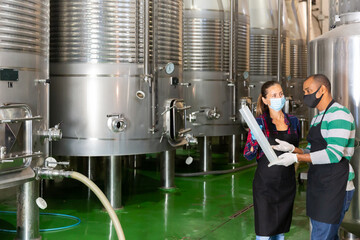Man and woman in protective mask with beaker in a winery shop