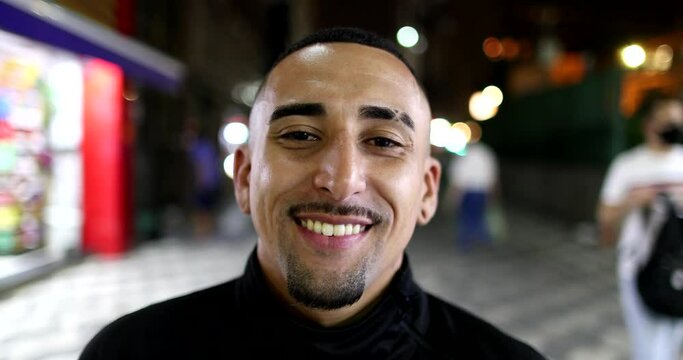 Brazilian hispanic man smiling at camera in city at night