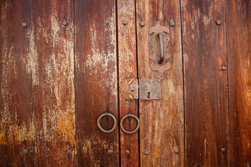 Fototapeta premium Close up view to a wooden weathered door with door rings in historic town Barichara, Colombia 