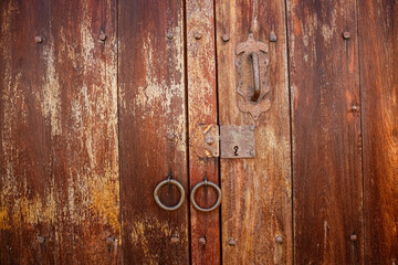 Close up view to a wooden weathered door with door rings in historic town Barichara, Colombia
