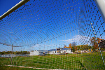 football goal net in an open stadium with a green lawn, autumn day