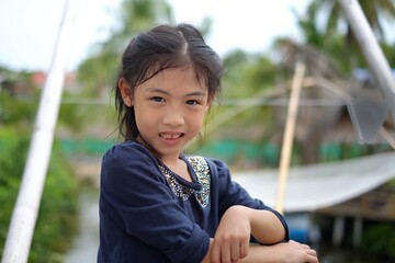 A half body shot of cute young Asian girl posing for the camera, feeling happy, smiling.