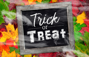 Black slate chalkboard with happy halloween and trick or treat pumpkin decoration with fog