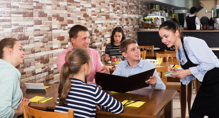 Positive cheerful waitress taking order from guests and writing into note