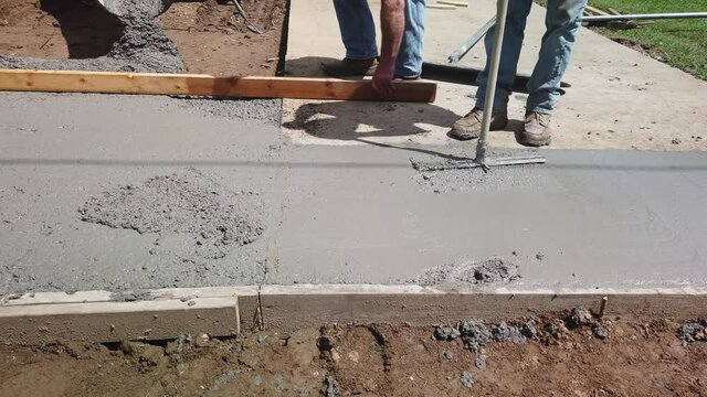 Man fixes a poured cement area where wet cement was stepped on