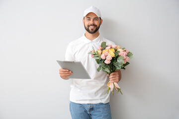 Delivery man with bouquet of flowers on light background