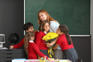 Schoolchildren greeting their teacher in classroom