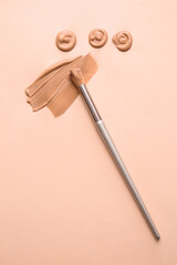 Samples of foundation for makeup and brush on color background