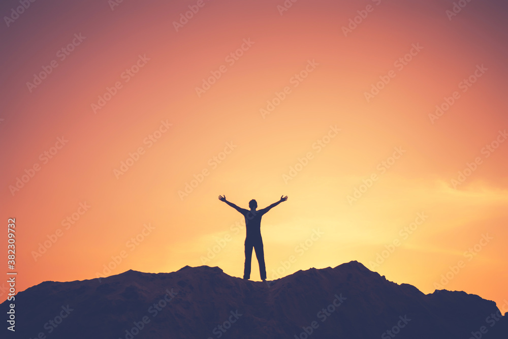 Wall mural copy space of man rise hand up on top of mountain and sunset sky abstract background.