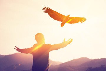 Man raise hand up on top of mountain and sunset sky with eagle bird fly abstract background.