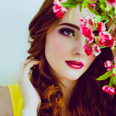 Beautiful white girl with flowers. Stunning ginger girl with flowers and  
butterflies. Closeup face of young beautiful woman with a healthy clean skin. Pretty woman with bright makeup