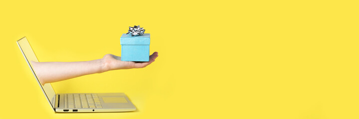 Giving a gift from the screen of the computer online yellow background and blue present with the...