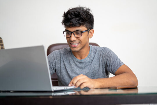 Indian Teenager Working On His Laptop. Concentration And Work From Home Concept.