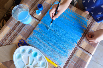 the girl draws blue gouache cardboard, makes a background, sits in the home kitchen