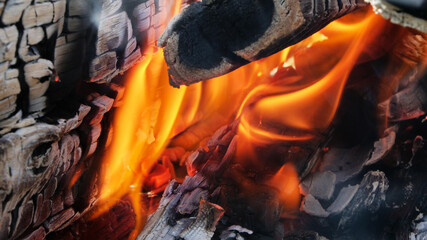 Glowing embers in hot red color, abstract background. The hot embers of burning wood log fire. Firewood burning on grill. Texture fire bonfire embers.