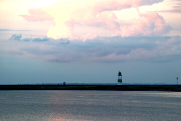 Obraz na płótnie Canvas Pink colored clouds reflected in the sea and coast with lighthouse of Schleimünde - dusk