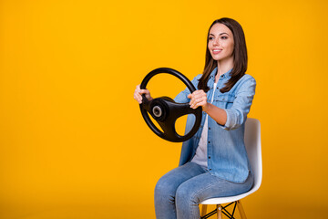 Profile photo of pretty funny lady good mood sit chair hold steering wheel riding imagine car driving auto license examination wear casual denim shirt isolated yellow color background