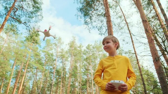 Child launches the drone outdoors. Boy plays with a quadrocopter on the nature. White boy is learning  to control a drone in the Park.