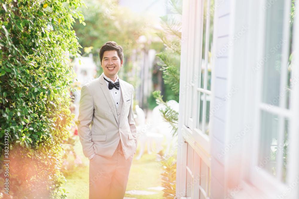 Wall mural asian man standing outdoors wearing a suit.