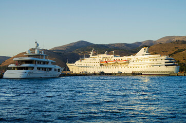 Classic cruiseship or cruise ship liner with motor yacht in port of Kefalonia in Greece during...