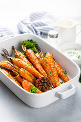 baked carrots in a ceramic form on a light background, close-up, selective focus