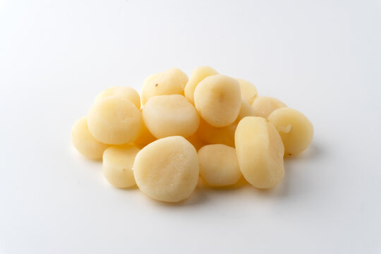 A pile of cooked and peeled water chestnuts on a white background.