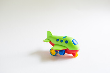 Toy green plastic airplane with colored red, blue, yellow details on a white background. Toy for a child, the concept of tourism and travel, air travel. Space for text