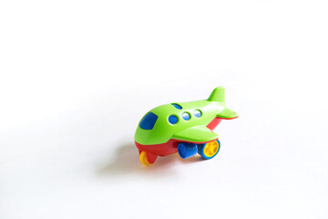 Toy green plastic airplane with colored red, blue, yellow details on a white background. Toy for a child, the concept of tourism and travel, air travel. Space for text